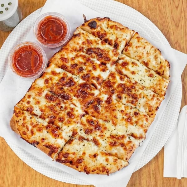 Cheesy garlic breadsticks, cut into strips, served with two small cups of marinara sauce.
